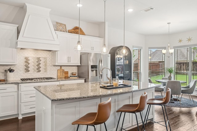 13002 Clarendon Dr, Frisco, TX 75035 - kitchen featuring stainless steel appliances, a kitchen island with sink, visible vents, dark wood-type flooring, and custom range hood