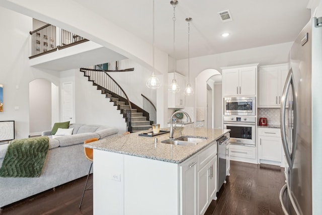 13002 Clarendon Dr, Frisco, TX 75035 - kitchen with visible vents, a sink, open floor plan, arched walkways, and appliances with stainless steel finishes