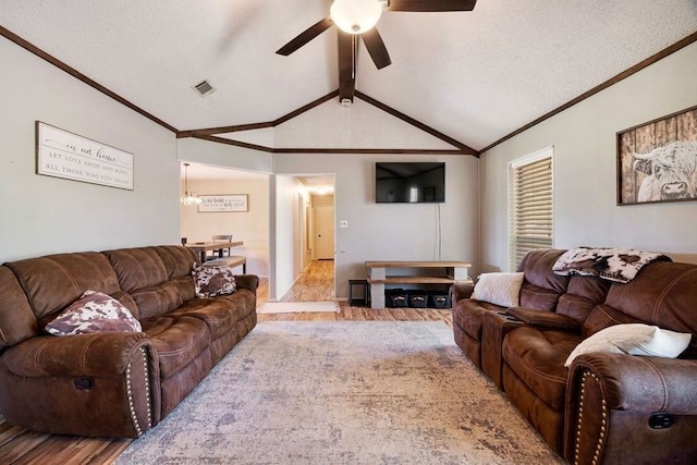living area featuring vaulted ceiling, wood finished floors, visible vents, ornamental molding, and ceiling fan