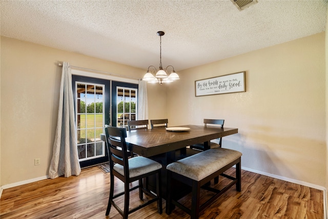 dining room featuring visible vents, baseboards, wood finished floors, and a textured ceiling
