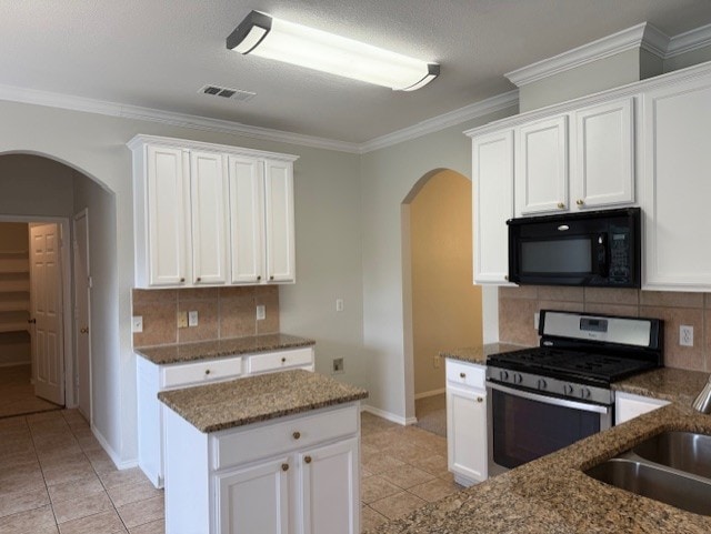 kitchen with arched walkways, light tile patterned flooring, black microwave, and gas stove