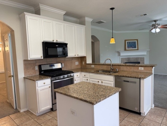 kitchen with a sink, a peninsula, arched walkways, a ceiling fan, and appliances with stainless steel finishes