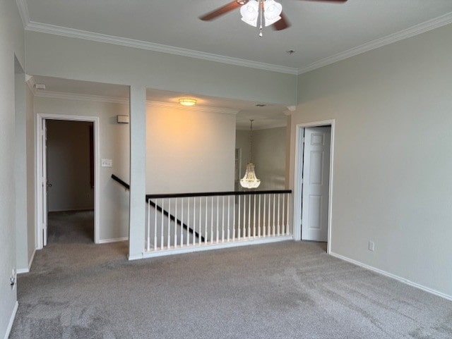 spare room with carpet floors, ornamental molding, baseboards, and a ceiling fan