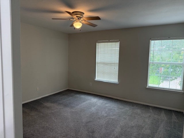 spare room with baseboards, ceiling fan, and dark carpet