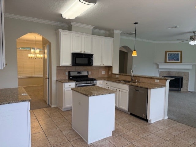 kitchen featuring arched walkways, a sink, white cabinets, ceiling fan with notable chandelier, and stainless steel appliances