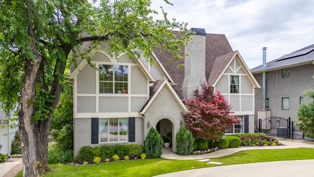 6726 Williamson Rd, Dallas, TX 75214 - tudor-style house with brick siding, stucco siding, a chimney, a gate, and a front lawn