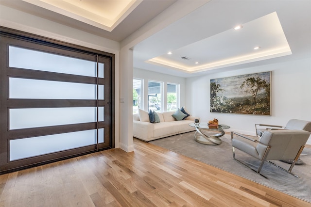entrance foyer with recessed lighting, baseboards, wood finished floors, a tray ceiling, and visible vents