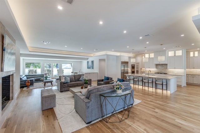 living room featuring a fireplace, recessed lighting, light wood-style flooring, and visible vents