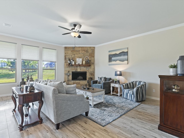 living room with a stone fireplace, visible vents, crown molding, baseboards, and ceiling fan