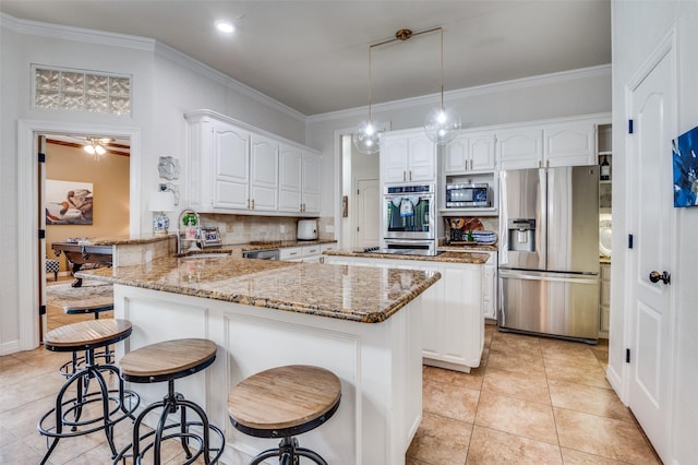 kitchen featuring stainless steel appliances, a peninsula, a sink, white cabinetry, and light stone countertops
