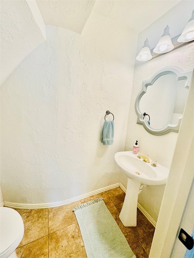 half bathroom featuring baseboards, toilet, and tile patterned flooring