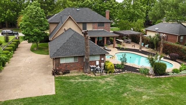 back of property with brick siding, a patio area, a lawn, and an outdoor pool