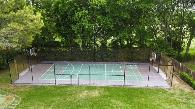 view of basketball court with a yard, a tennis court, and fence
