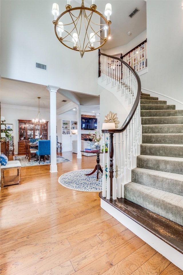 entrance foyer with stairway, a high ceiling, visible vents, and an inviting chandelier