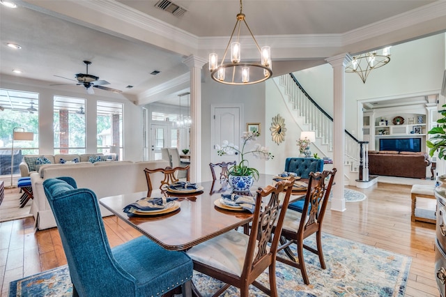 dining room with stairs, ceiling fan with notable chandelier, light wood finished floors, visible vents, and ornate columns