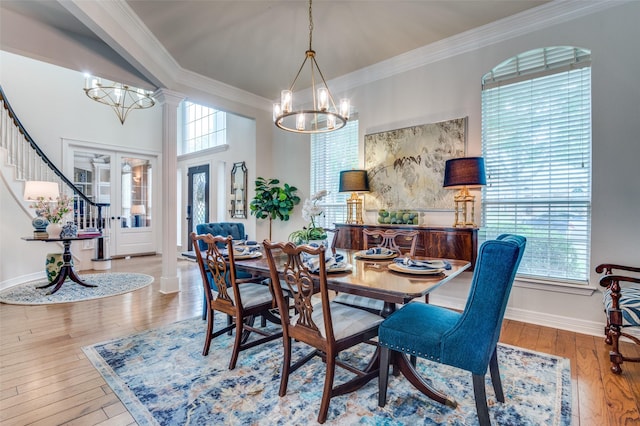 dining room with hardwood / wood-style floors, an inviting chandelier, ornamental molding, baseboards, and stairs