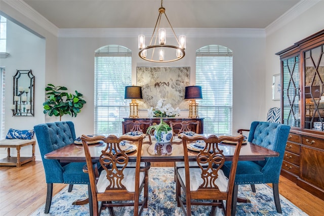 dining area featuring crown molding, a chandelier, and light wood finished floors
