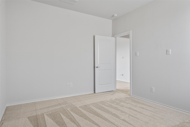 empty room featuring baseboards and light carpet