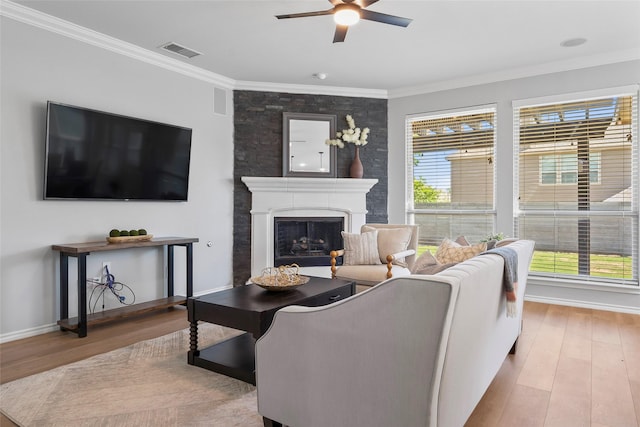 living area with crown molding, a ceiling fan, visible vents, and wood finished floors