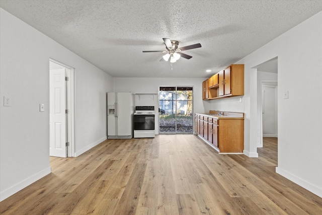 kitchen featuring brown cabinetry, white fridge with ice dispenser, ceiling fan, electric range oven, and light wood-style flooring