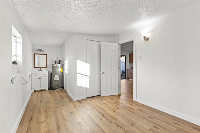 interior space featuring water heater, light wood-style flooring, a textured ceiling, and a sink