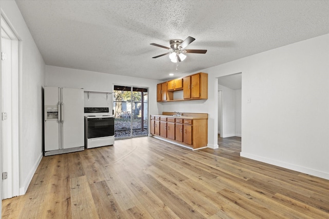 kitchen featuring light wood finished floors, a sink, white appliances, a textured ceiling, and ceiling fan