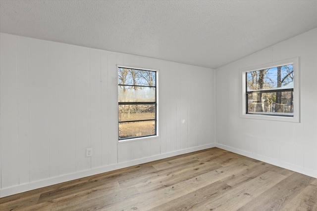 empty room with wood finished floors, a textured ceiling, and a healthy amount of sunlight