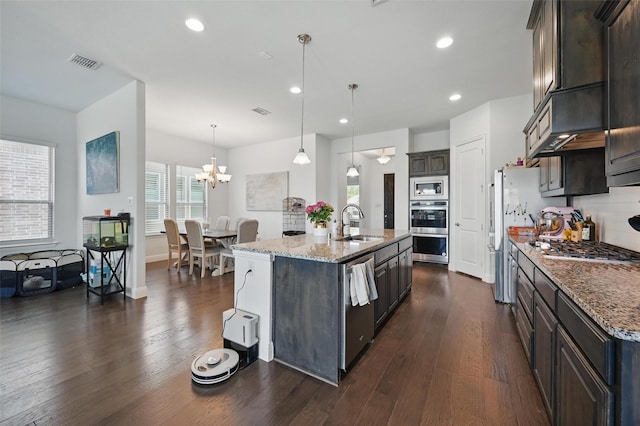 kitchen with light stone counters, appliances with stainless steel finishes, a sink, and dark wood-type flooring