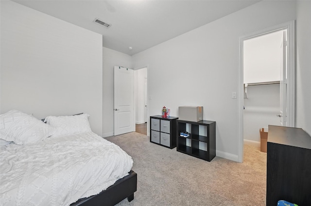 carpeted bedroom with a spacious closet, baseboards, and visible vents