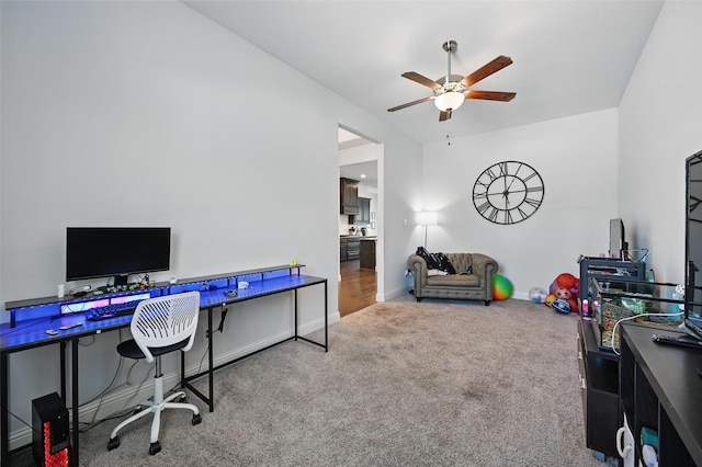 carpeted office space featuring baseboards and ceiling fan