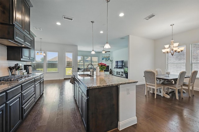 kitchen with stainless steel gas cooktop, a sink, dark wood-style flooring, visible vents, and baseboards