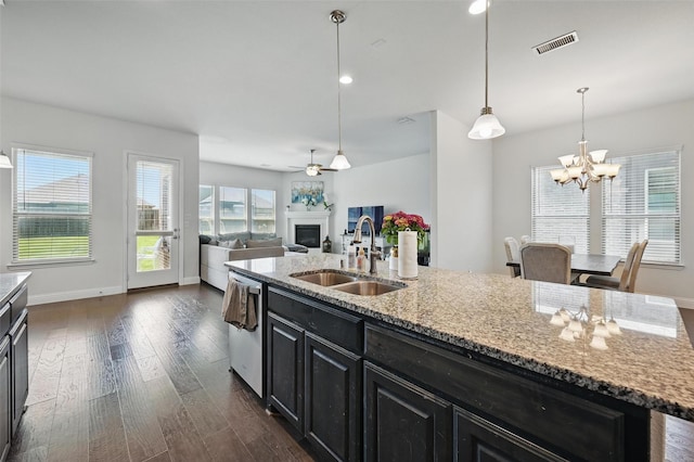 kitchen with stainless steel dishwasher, a sink, visible vents, dark cabinets, and a fireplace