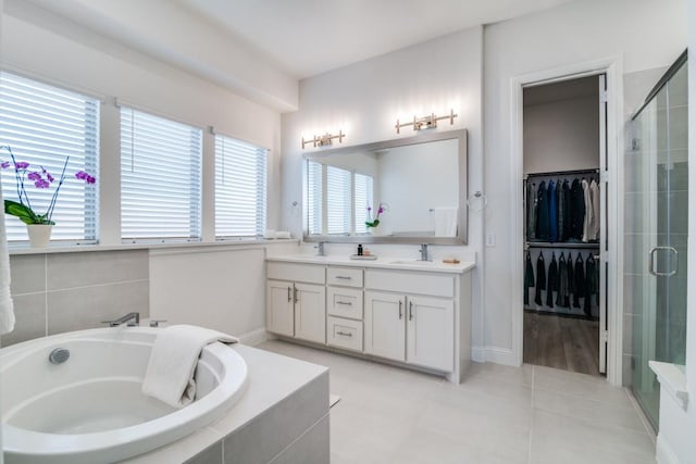 full bathroom featuring a bath, a sink, double vanity, and a stall shower