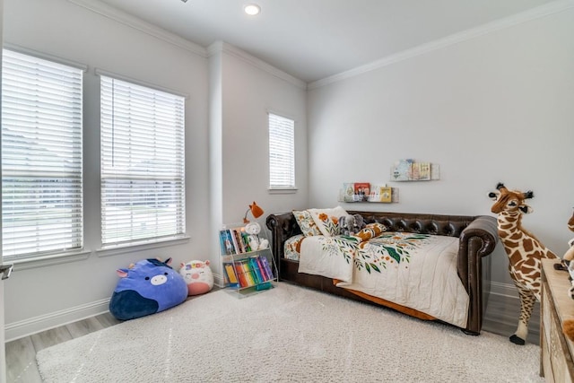 bedroom featuring wood finished floors, ornamental molding, baseboards, and multiple windows