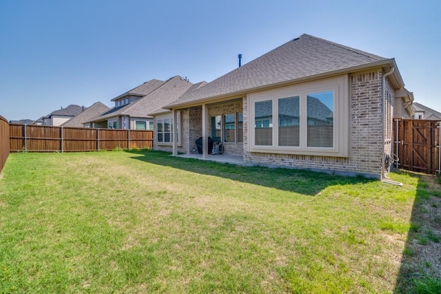 back of house featuring a fenced backyard, brick siding, and a lawn
