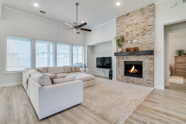 living area featuring wood finished floors, visible vents, baseboards, a fireplace, and ceiling fan