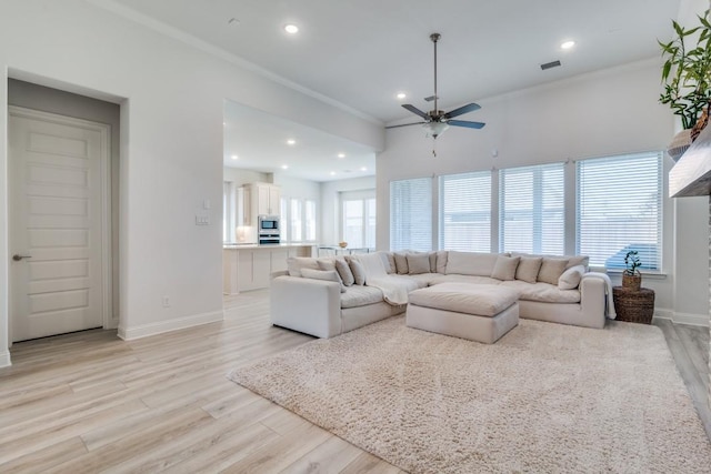 living area with light wood-style flooring, visible vents, ceiling fan, and crown molding