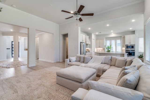living room with light wood-type flooring, baseboards, recessed lighting, ceiling fan, and ornamental molding