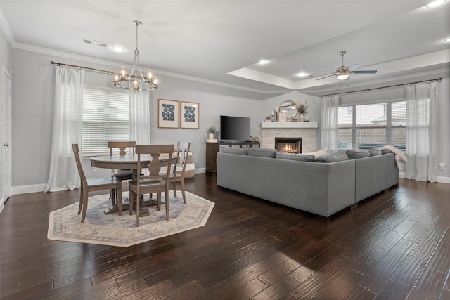 living room with ceiling fan with notable chandelier, a glass covered fireplace, and baseboards