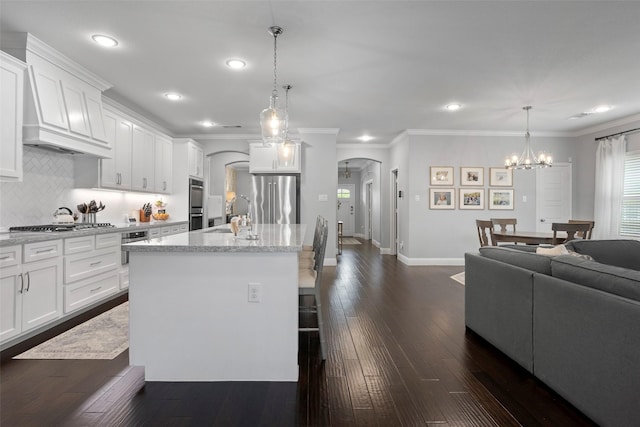 kitchen featuring arched walkways, appliances with stainless steel finishes, dark wood-style flooring, and recessed lighting