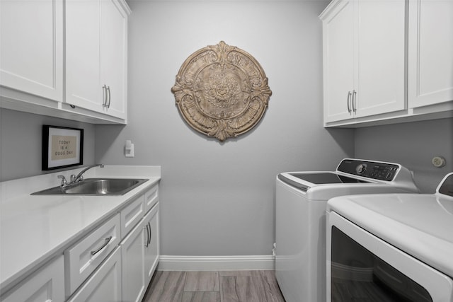 laundry room featuring washing machine and dryer, baseboards, cabinet space, and a sink