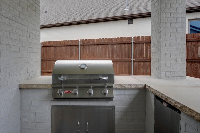 view of patio featuring fence, exterior kitchen, and a grill
