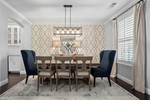dining area with baseboards, wood finished floors, visible vents, and crown molding