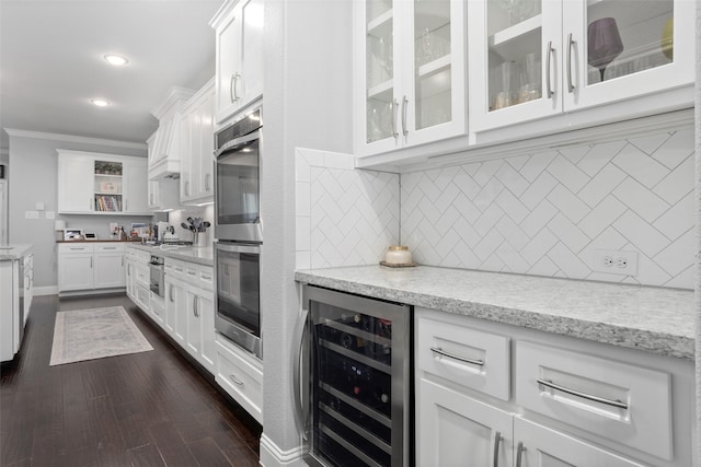 interior space with open shelves, beverage cooler, double oven, white cabinetry, and ornamental molding