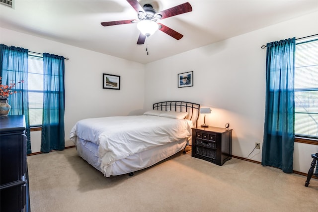 carpeted bedroom with visible vents, baseboards, and ceiling fan