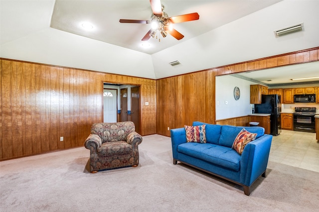 living room featuring light carpet, wooden walls, visible vents, and ceiling fan