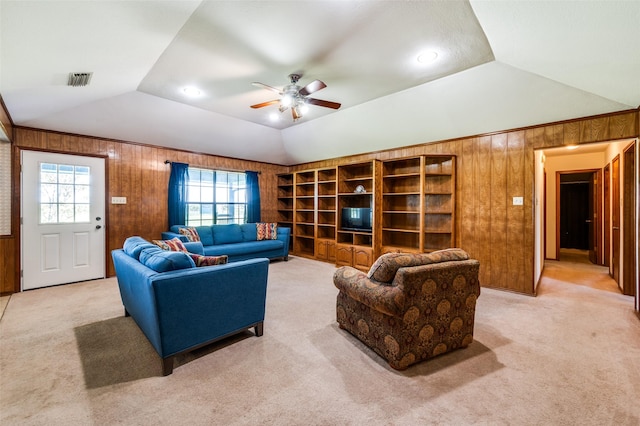 carpeted living room featuring ceiling fan, lofted ceiling, wood walls, and visible vents