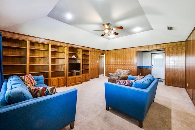 living room with vaulted ceiling, a ceiling fan, carpet, wood walls, and visible vents