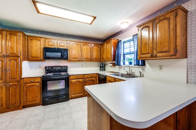 kitchen with a sink, black appliances, brown cabinets, light countertops, and a peninsula