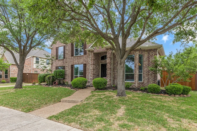 traditional-style house featuring fence, a front lawn, and brick siding